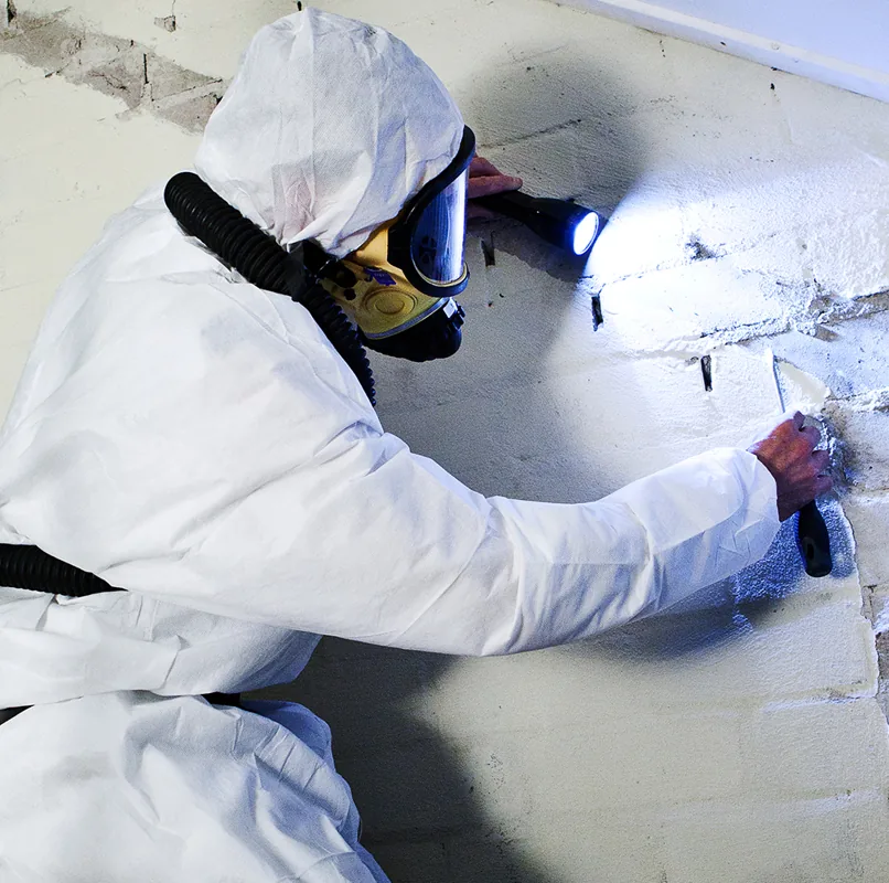 Licensed operative removing asbestos insulating board inside a domestic property Asbestos Removal Team Ltd