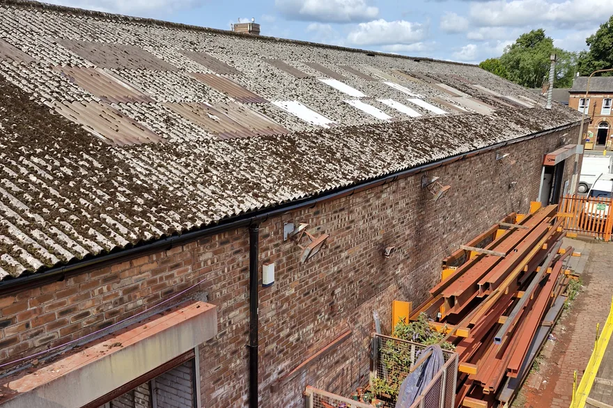 Commercial roof strip out with waste skips and site plant during asbestos removal Asbestos Removal Team Ltd